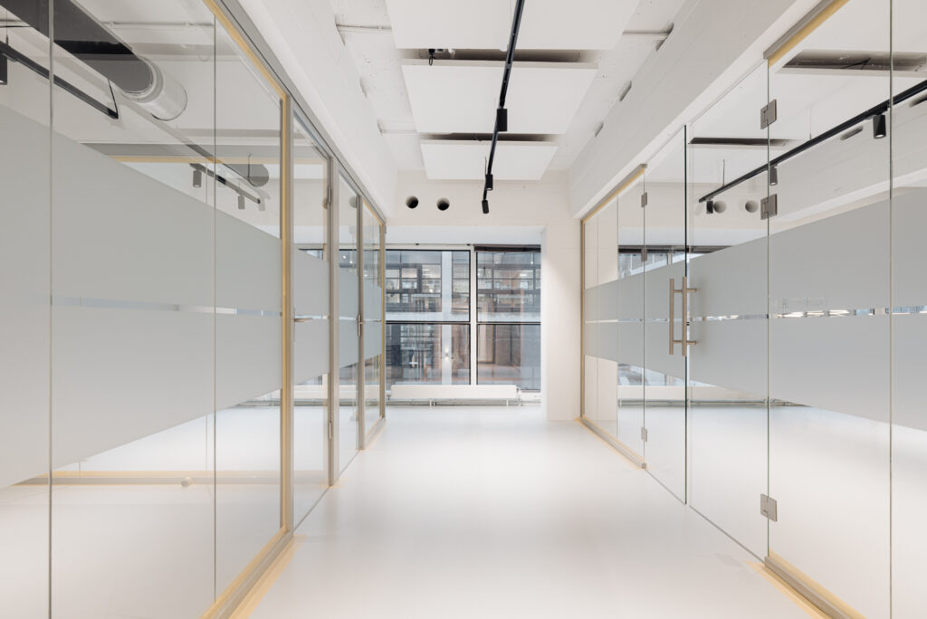 Moderne, lichte kantoorruimte aan de Generaal Vetterstraat met glazen wanden en zicht op een gebouw met grote ramen.